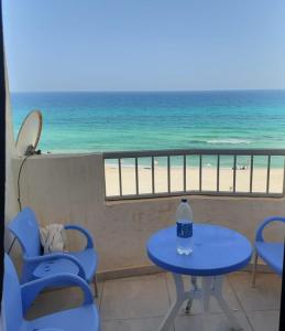 una mesa con una botella de agua en un balcón con vistas a la playa en family condo with panoramic sea view, en Alejandría