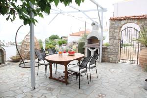 a patio with a table and chairs and an outdoor oven at Despoina Apartment in Patitiri