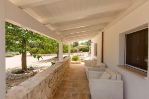 a patio with chairs and a tv and a wall at Tenuta Sardella by BarbarHouse in Latiano
