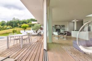 eine Holzterrasse mit einem Tisch und Stühlen darauf in der Unterkunft Villa d'architecte avec piscine en Béarn in Salies-de-Béarn