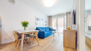 a living room with a blue couch and a table at Apartamenty Sun & Snow Kasprowicza in Kołobrzeg
