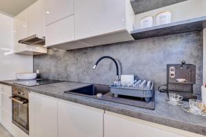 - une cuisine avec un évier et des placards blancs dans l'établissement Beautiful new apartment Blaz, à Mali Lošinj