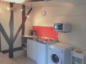 a small kitchen with a washing machine and a microwave at Maison charmante à Souvigny-en-Sologne avec jardin in Souvigny-en-Sologne