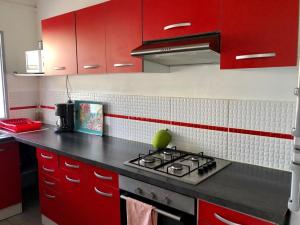 a kitchen with red cabinets and a stove top oven at Zandoli Cottage in Les Galets
