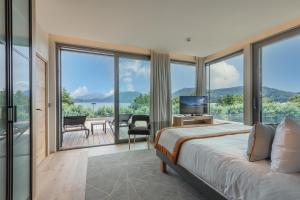 a bedroom with a bed and a balcony with a television at Rivage Hôtel & Spa Annecy in Annecy
