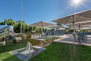 a fountain in a park with tables and umbrellas at Rivage Hôtel & Spa Annecy in Annecy