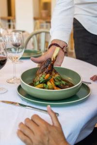 a person is serving a plate of food on a table at Domaine Les Sources de Dieulefit in Dieulefit