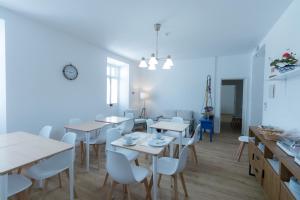 un comedor con mesas blancas y sillas blancas en Lagoa Hostel & Suites, en Lagoa