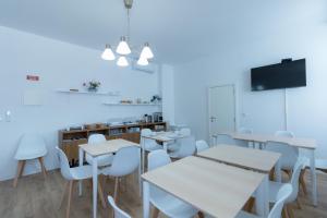 a dining room with white tables and white chairs at Lagoa Hostel & Suites in Lagoa