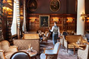 a woman walking through a room with tables and chairs at Hotel Le Negresco in Nice