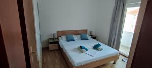 a bedroom with a bed with blue pillows and a window at Ap Nada in Rogoznica