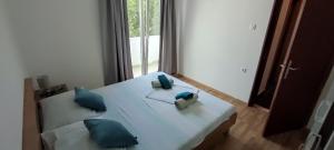a white bed with blue pillows in a room at Ap Nada in Rogoznica