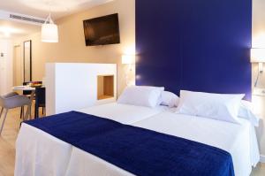 a bedroom with a large bed with a blue wall at Apartamentos Mayal con Piscina in Benidorm