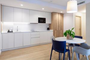 a kitchen with white cabinets and a table and chairs at Apartamentos Mayal con Piscina in Benidorm