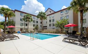 een zwembad met stoelen en parasols voor een gebouw bij Red Roof Inn PLUS + Gainesville in Gainesville