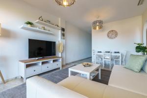 een woonkamer met een witte bank en een tv bij Chic Beachfront Flat with Amazing Sea Views and Private Indoor Parking in Benalmádena