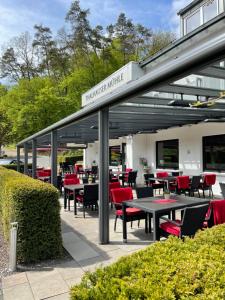 Thalhauser Mühle Hotel-Restaurant في Thalhausen: مطعم يوجد به كراسي حمراء وطاولات في مبنى