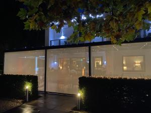 Thalhauser Mühle Hotel-Restaurant في Thalhausen: منزل به نوافذ زجاجية في الليل مع أضواء