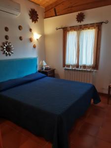 a bedroom with a blue bed and a window at Giannella Tuscany Holidays in Giannella