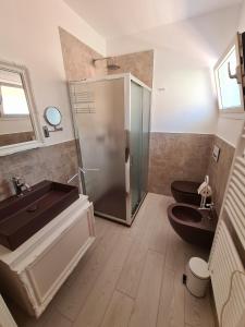 a bathroom with a shower and a sink and two toilets at L'Isola nel Parco Boutique Rooms & Apartments in La Maddalena