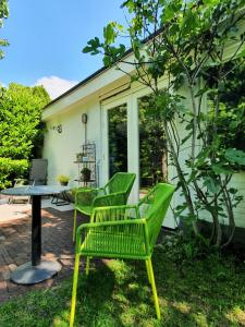 two green chairs and a table in front of a house at Bed and Breakfast en Studio Het Atelier in Goirle