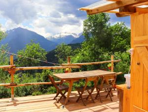 a wooden table and chairs on a deck with mountains at Glamping la Cascina d'Orleans in Saint-Pierre
