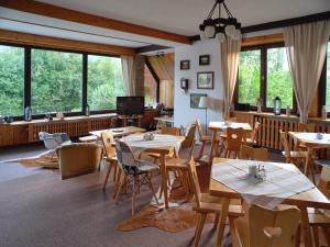 un restaurante con mesas y sillas de madera y ventanas en B&B Art House Szymaszkowa 1, en Zakopane