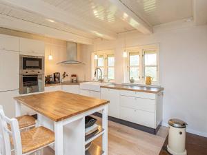 a kitchen with white cabinets and a wooden table at 8 person holiday home in Vig in Vig