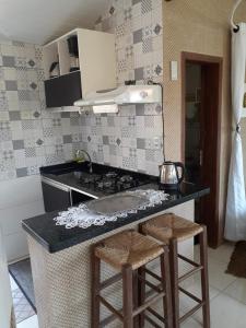 a kitchen with a counter with a stove and stools at Casas Ferrugem-Garopaba in Garopaba