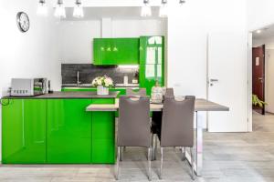 a kitchen with green cabinets and a table with chairs at InLuce Apartment Top Class in Sanremo