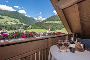 un tavolo con bicchieri da vino su un balcone con vista di Alpenchalet Niederkofler Vera a San Giovanni in Val Aurina Altre 10 foto