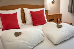 2 cuscini a forma di cuore su un letto con cuscini rossi di Alpenchalet Niederkofler Vera a San Giovanni in Val Aurina