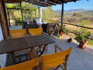 a patio with a wooden table and yellow chairs at Cosy Calm Cottage in olive trees with sea view in Ermioni
