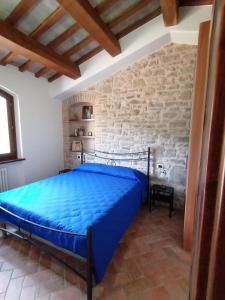 a bedroom with a blue bed in a stone wall at CASA LINARA in Frontino