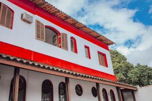a red and white building with red windows at Pousada Chale Suísso in Ilhabela