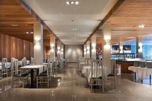 a restaurant with white tables and chairs and a bar at Hotel Rosa Nàutica in Malgrat de Mar