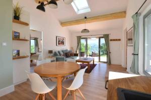 Luxury countryside cottage with mountain views في Roquefixade: مطبخ وغرفة معيشة مع طاولة وكراسي خشبية