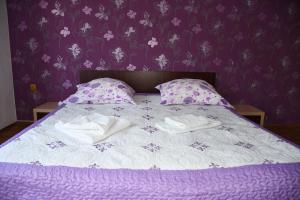 a purple bedroom with a bed with towels on it at VILA SIMONA in Moieciu de Sus