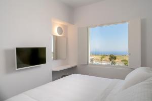 a white bedroom with a bed and a window at Lilium Homes in Karterados