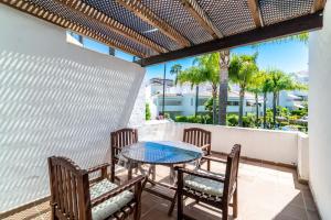 patio ze stołem, krzesłami i palmami w obiekcie Marbella Villa Monteros w Marbelli