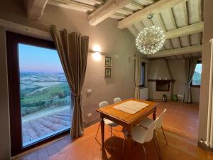 ein Esszimmer mit einem Tisch und einem großen Fenster in der Unterkunft Poggio ai Gelsi in Pienza