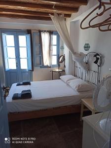 a bedroom with a bed and two windows at Traditional stone house with breathtaking view in Serifos Chora