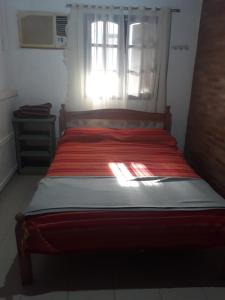 a bed in a room with a window with a red blanket at Hermosa Casita II Paso Patria in Paso de la Patria
