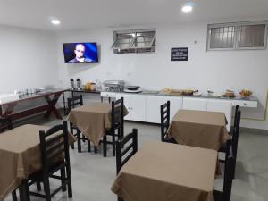 a dining room with tables and a kitchen with a tv at Hotel Saint Lucas in Sao Paulo