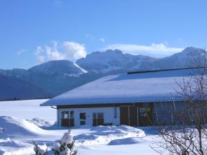 a building covered in snow with mountains in the background at Ferienwohnung Zottnerhof in Frasdorf