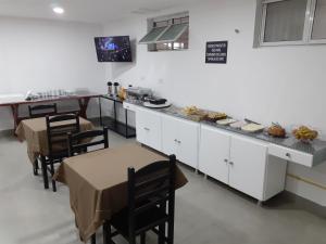 a kitchen with tables and chairs and a counter with food at Hotel Saint Lucas in São Paulo