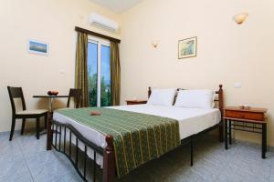 a bedroom with a bed and a table and a window at Hotel Loula Rooms and Apartments in Kamena Vourla