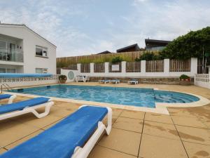 a large swimming pool with two blue chairs and a building at 7 Europa Court in Newquay