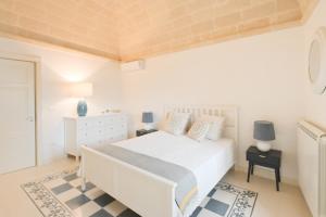 a white bedroom with a white bed and a dresser at Pietro Maggi - Apulian Historical House in Manduria