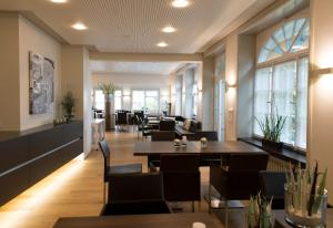 a dining room with tables and chairs and windows at Gasthaus zum Bahnhof in Berg